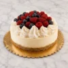 Clásico cheesecake redondo con una base de galleta crujiente, decorado elegantemente con un anillo de rosetones de crema batida blanca y un centro rebosante de frutos rojos frescos, incluyendo frambuesas y arándanos. Castillo's Cake Shop.