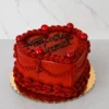 Pastel en forma de corazón cubierto completamente con un intenso glaseado color rojo oscuro. Su diseño clásico incluye detalles de puntos, drapeados elaborados, esferas rojas brillantes decorativas y el mensaje "Happy Birthday Veronica." escrito en negro. Castillo's Cake Shop.