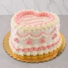 Pastel en forma de corazón con una base de glaseado blanco y delicados detalles estilo vintage en color rosa, que incluyen elegantes guirnaldas y bordes de concha. En la superficie lleva el mensaje "Feliz Cumpleaños Veronica" en caligrafía de glaseado rosa. Castillo's Cake Shop.