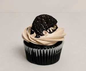 Irresistible cupcake de chocolate oscuro con un suave copete de glaseado en tono moka o galleta, coronado con una Oreo y un escurrimiento de jarabe de chocolate. Castillo's Cake Shop.