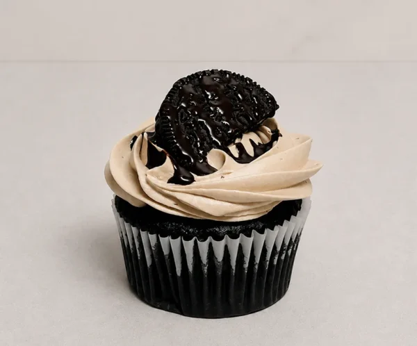 Irresistible cupcake de chocolate oscuro con un suave copete de glaseado en tono moka o galleta, coronado con una Oreo y un escurrimiento de jarabe de chocolate. Castillo's Cake Shop.