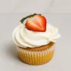 Tradicional cupcake de vainilla cubierto con un perfecto y cremoso remolino de glaseado blanco, decorado de forma fresca con la mitad de una jugosa fresa natural en la cima. Castillo's Cake Shop.