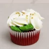 Esponjoso cupcake red velvet con un generoso remolino de glaseado blanco, acentuado con elegantes perlas doradas esparcidas en la superficie y hojitas de glaseado verde. Castillo's Cake Shop.