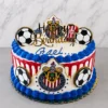 Pastel redondo con temática del equipo Chivas. Cubierta blanca con un goteo (drip) rojo vibrante y gruesos bordes de rosetones azules. Decorado con escudos del Club Deportivo Guadalajara, balones, una camiseta del equipo en la parte superior, el nombre "Gael" en glaseado azul y un letrero dorado de "Happy Birthday". Castillo's Cake Shop.