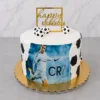 Pastel redondo con cubierta blanca y detalles de hexágonos de fondant formando un patrón de balón de fútbol en los costados. En el centro presenta una gran imagen comestible de Cristiano Ronaldo (CR7) con el uniforme del Real Madrid. Está coronado con tres pequeños balones de fútbol y un letrero geométrico dorado de "happy BIRTHDAY". Castillo's Cake Shop.