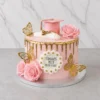 Llamativo pastel redondo de un piso con cobertura rosa pastel y un escurrimiento (drip) dorado metálico en el borde superior. Está adornado con rosas rosadas, mariposas doradas 3D, un birrete rosa a juego con un diploma en la corona, y una placa central blanca con perlas doradas que dice "CONGRATS PILLY CLASS OF 2025". Castillo's Cake Shop.