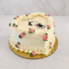 Hermoso pastel en forma de corazón con glaseado blanco y decoración vintage estilo Lambeth. Presenta bordes acanalados, guirnaldas y delicadas rosas rosadas de glaseado con hojas verdes. En el centro luce una tierna imagen comestible de Snoopy graduado saltando de felicidad, acompañada de la palabra "Congrats!!". Castillo's Cake Shop.
