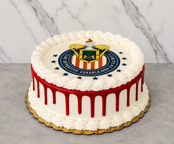Pastel redondo con temática del Club Deportivo Guadalajara (Chivas). Presenta una cobertura blanca lisa con un vibrante escurrimiento (drip) de color rojo y clásicos bordes de glaseado en forma de concha en la base y la corona. En la superficie luce el escudo del equipo impreso en una gran oblea comestible rodeada de estrellas. Castillo's Cake Shop.