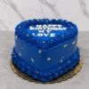 Romántico pastel en forma de corazón cubierto con un intenso glaseado azul rey. Está decorado con elaborados bordes entrelazados en la base y la corona, salpicado con pequeñas perlas doradas y delicados destellos de hoja de oro. En la superficie lleva el mensaje "HAPPY BIRTHDAY MY LOVE" en letras blancas gruesas. Castillo's Cake Shop.
