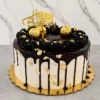 Elegante pastel redondo con cobertura blanca y un apetitoso escurrimiento (drip) de chocolate oscuro. Los costados están adornados con toques de hoja de oro. La corona está decorada con un anillo de tupidos rosetones de glaseado negro con perlas doradas, tres chocolates Ferrero Rocher y un letrero dorado superior de "Happy Birthday". Castillo's Cake Shop.