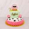 Tierno pastel de dos pisos con temática de animales de granja. El piso inferior es blanco con manchas de vaca negras y un abundante borde de rosetones en color rosa fuerte. El piso superior es verde menta pastel, lleva el nombre "Ayleen" en dorado y pequeñas margaritas. Está coronado con el número "2" dorado, un patito y una adorable figura de un granerito rosa asomando un cerdito, un caballo y una vaca. Castillo's Cake Shop.