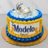 Llamativo pastel redondo que simula una hielera rebosante. Sus costados están cubiertos con el logo clásico de Cerveza Modelo Especial impreso en oblea, rodeado por decorativos rosetones en azul eléctrico y amarillo. La superficie está llena de grandes cubos de gelatina transparente simulando hielo, de donde emerge una lata real de Cerveza Modelo. Castillo's Cake Shop.