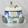 Sofisticado pastel redondo con base blanca y un intenso escurrimiento (drip) azul eléctrico brillante. Al frente exhibe la icónica etiqueta comestible de Tequila Don Julio Blanco. La corona está decorada con grandes copos de crema blanca, y el diseño se complementa con fresas bañadas en una cobertura azul grisáceo perlado. En el centro superior luce una botella miniatura real de Tequila Don Julio Blanco. Castillo's Cake Shop.