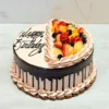 Pastel de Chocolate Tres Leches Pastel redondo con glaseado color moca claro texturizado y un marcado goteo de chocolate oscuro. La superficie está dividida por una línea de rosetones; un lado lleva el mensaje "Happy Birthday" en elegante letra cursiva negra, y el otro está cubierto de frutas frescas mixtas (fresas, duraznos, kiwi y frutos rojos).