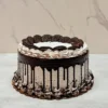 Pastel de Oreo Redondo 0 Pasteles redondos cubiertos con glaseado de cookies and cream con textura de líneas horizontales y un goteo de chocolate oscuro profundo. En la parte superior destacan mitades de galletas Oreo entrelazadas formando un círculo interior, rodeadas por rosetones de glaseado. El borde inferior está rematado con rosetones y migajas de galleta Oreo espolvoreadas.
